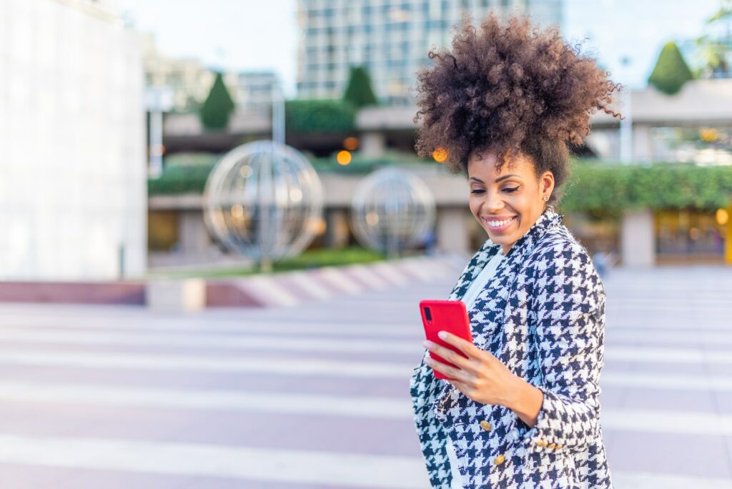 black afro woman looking happily to the phone