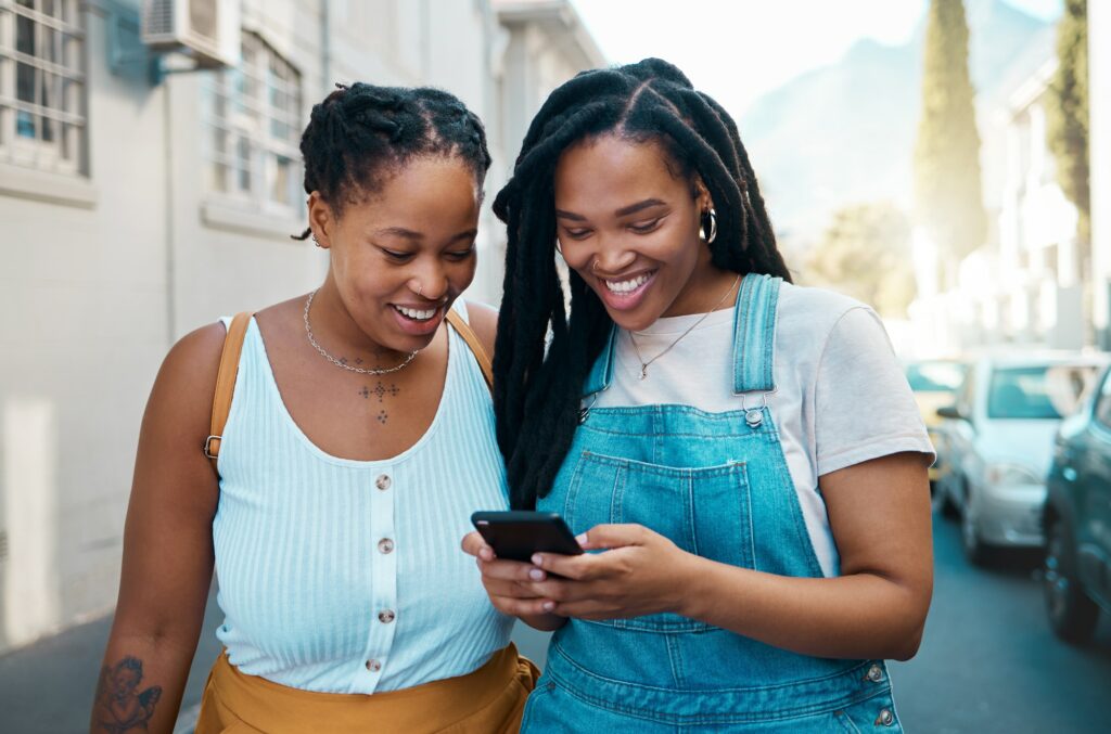 Happy black woman, friends and phone in social media communication, texting together outside an urb