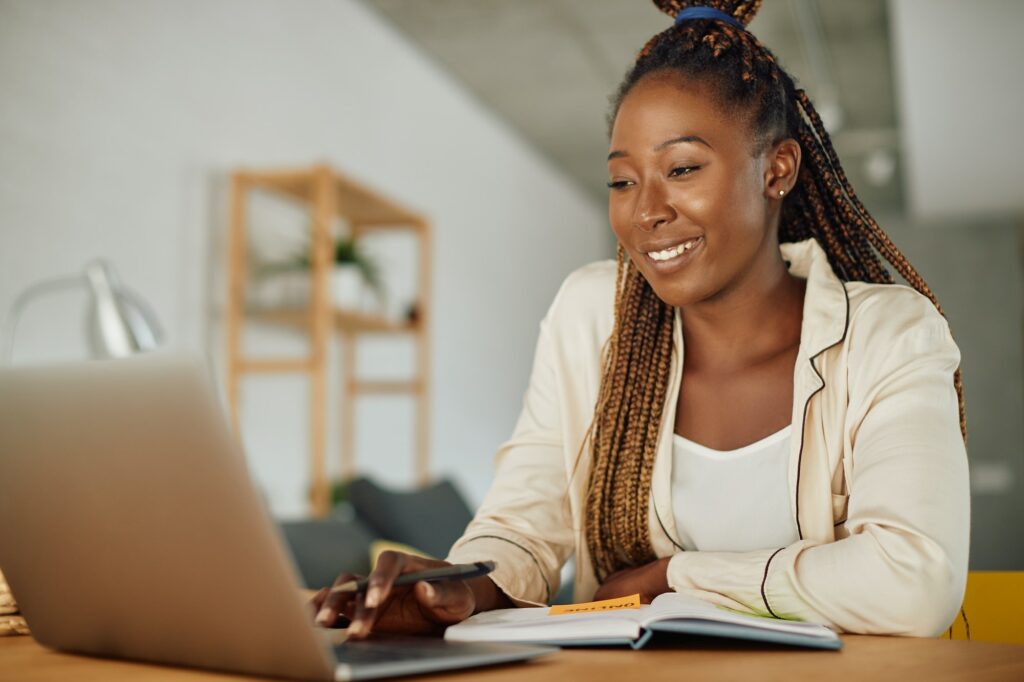 Young happy Africa American woman using laptop while working at home.